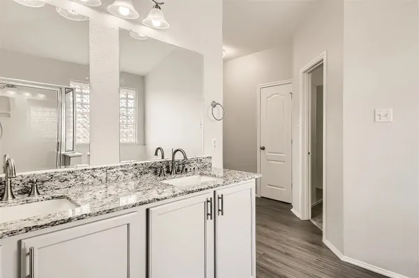 a bathroom with a granite countertop sink a mirror and a shower