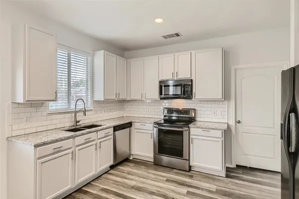 a kitchen with white cabinets sink and stainless steel appliances