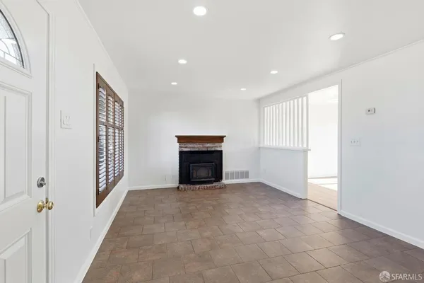 a view of an empty room with a fireplace and a window