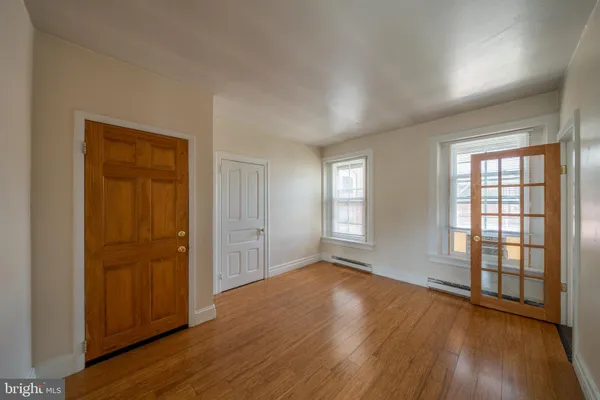 an empty room with wooden floor and windows