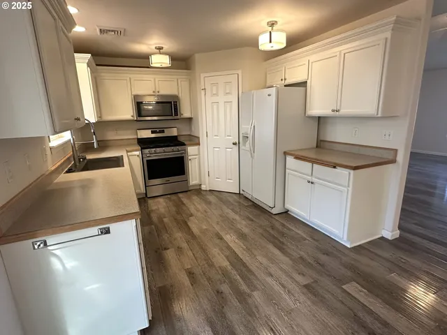 a kitchen with granite countertop a stove a refrigerator and a sink