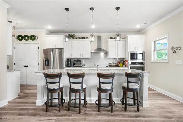 a kitchen with stainless steel appliances kitchen island granite countertop a table chairs and a refrigerator