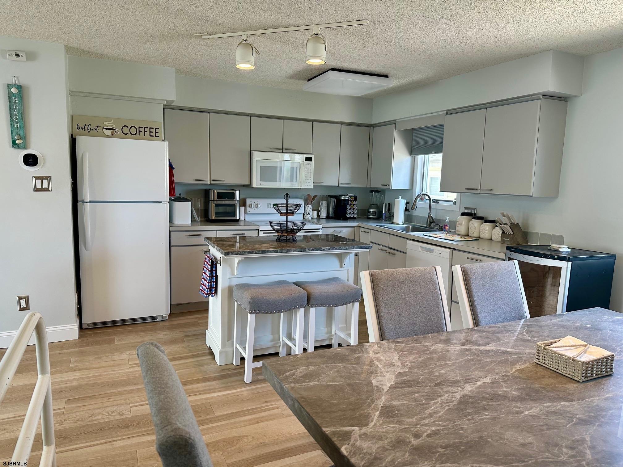 305 4th Street South, Unit 305 Brigantine, NJ 08203 - Photo 19 of 45 a kitchen with stainless steel appliances sink refrigerator dining table and chairs