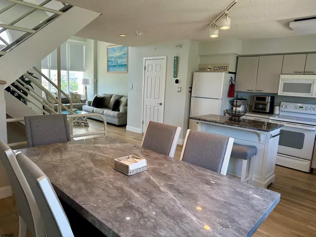 a living room with stainless steel appliances furniture a rug and a kitchen view