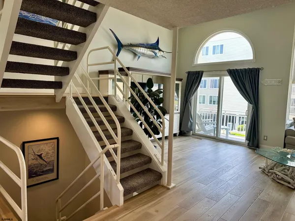 a living room with stainless steel appliances furniture a rug and a kitchen view