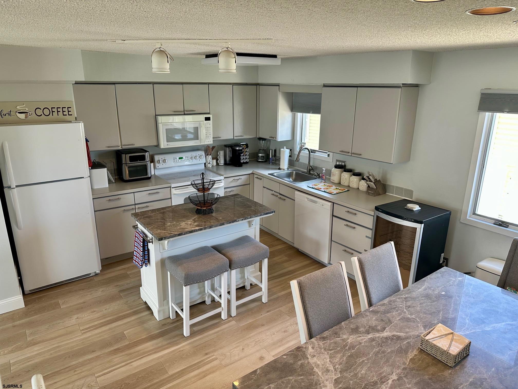 305 4th Street South, Unit 305 Brigantine, NJ 08203 - Photo 39 of 45 a kitchen with a refrigerator a stove a sink and white cabinets with wooden floor