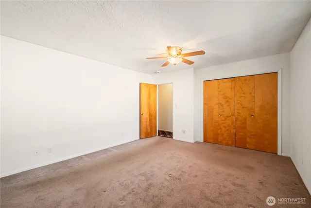 an empty room with a window and chandelier fan
