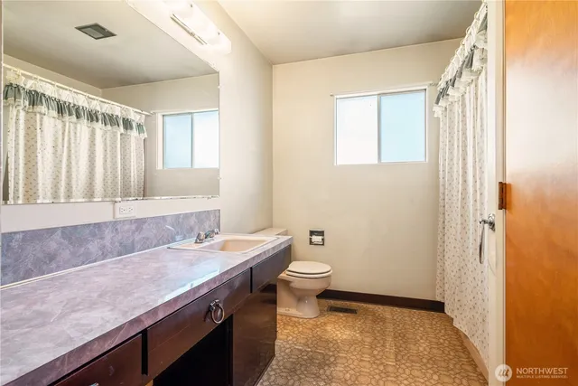 a bathroom with a granite countertop sink a toilet and shower