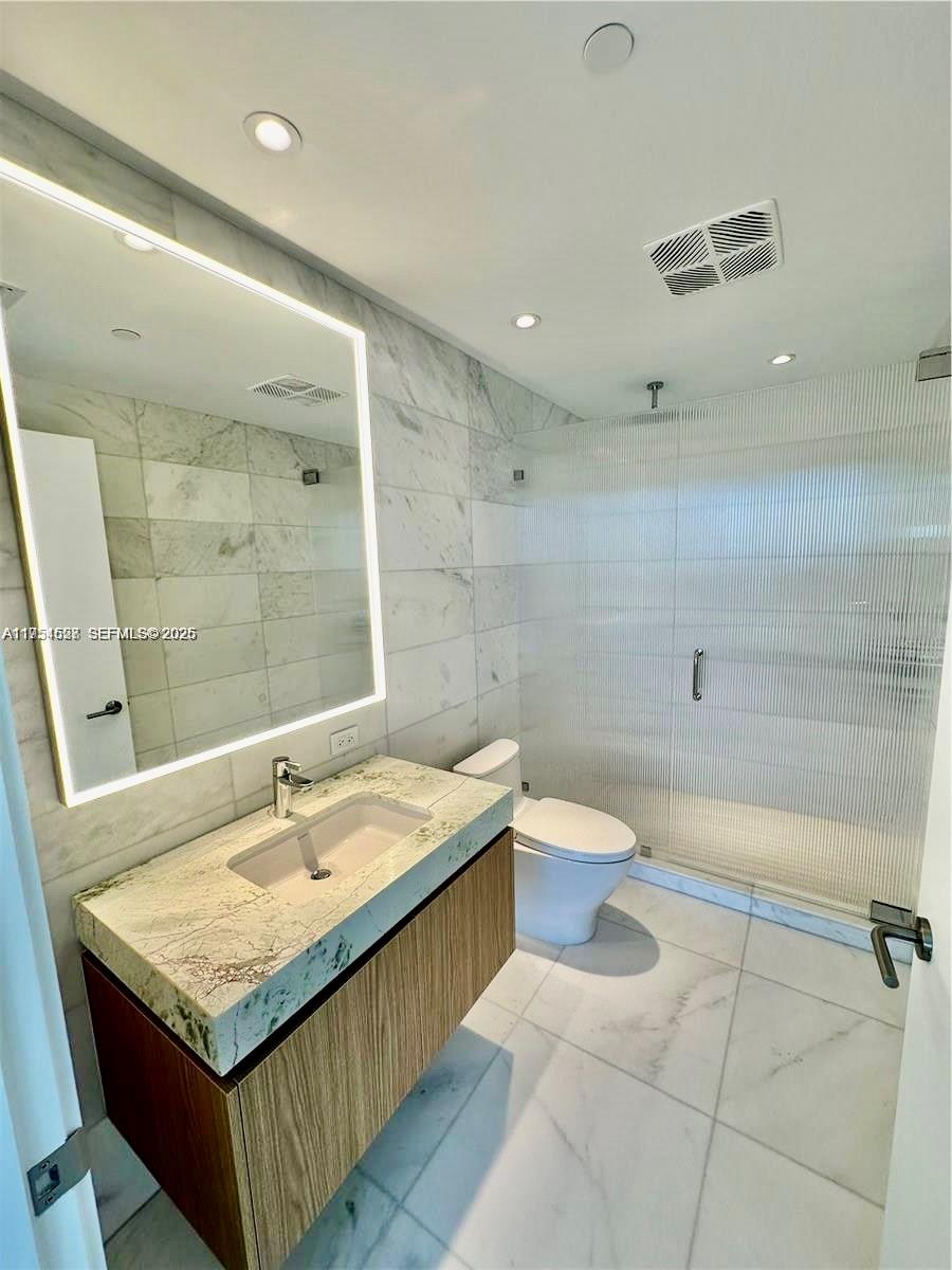500 Alton Road, Unit 1208 Miami Beach, FL 33139 - Photo 12 of 16 a bathroom with a granite countertop sink a toilet a mirror and shower