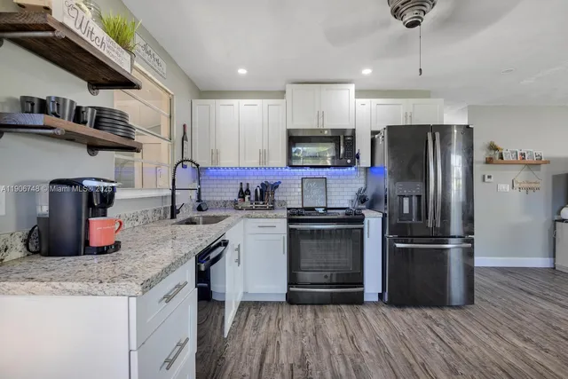a kitchen with stainless steel appliances granite countertop a refrigerator a stove top oven a sink and dishwasher