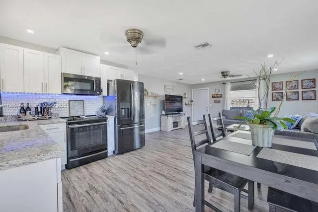 a kitchen with refrigerator a microwave and chairs