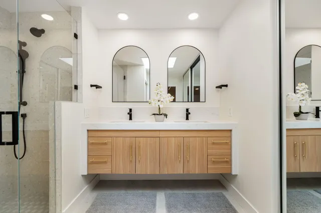 a spacious bathroom with a double vanity sink a mirror and shower