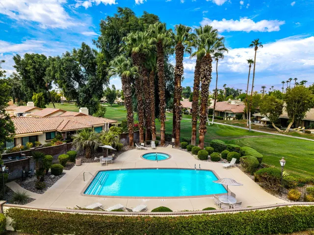 a view of a swimming pool with lawn chairs under an umbrella