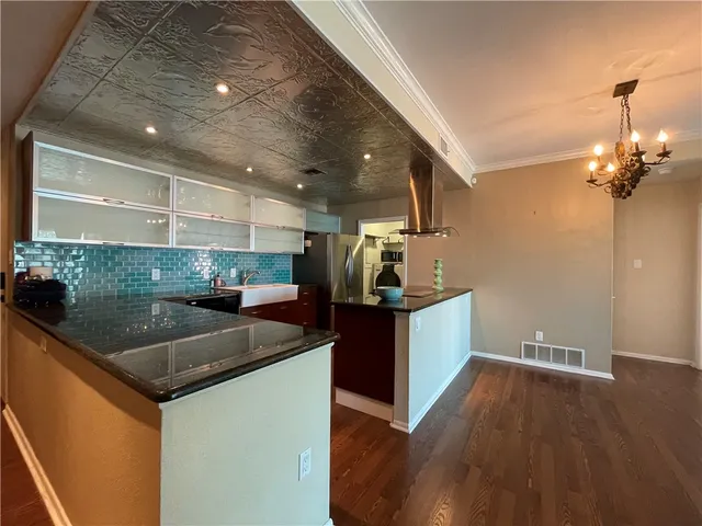a living room with stainless steel appliances with kitchen view