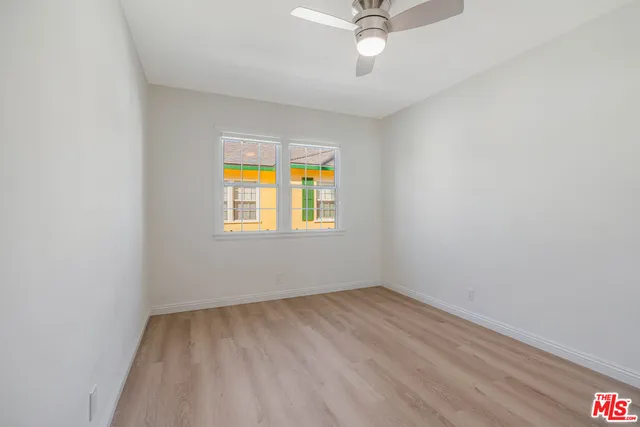 an empty room with a window and ceiling fan