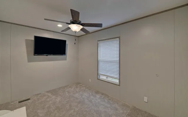 an empty room with ceiling fan and window