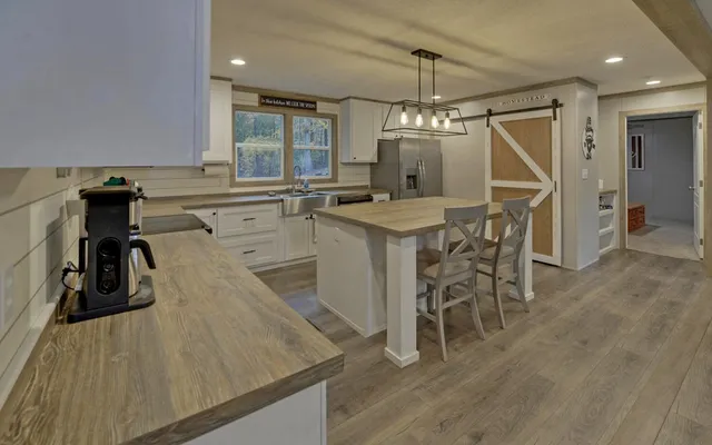 a kitchen with stainless steel appliances kitchen island granite countertop a table chairs refrigerator and cabinets