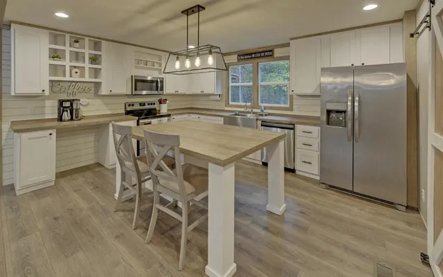 a kitchen with stainless steel appliances a sink a stove a refrigerator cabinets and a dining table