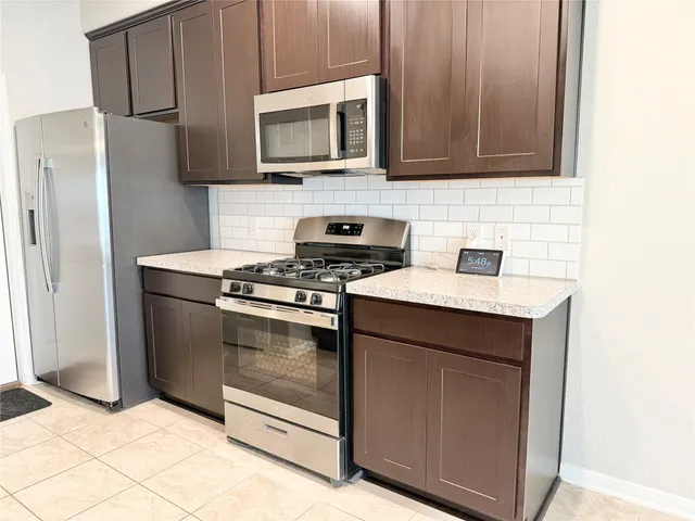a kitchen with granite countertop cabinets stainless steel appliances and a counter space