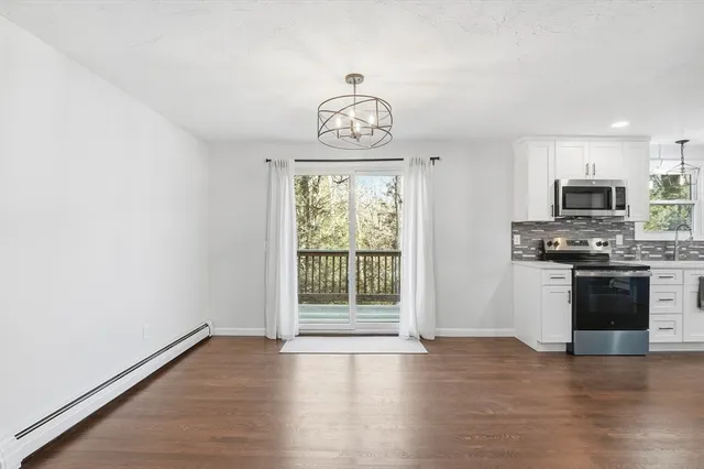 a view of an empty room with a kitchen and a window