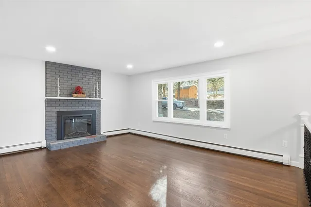an empty room with wooden floor fireplace and windows