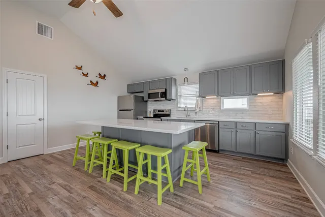 a kitchen with kitchen island granite countertop wooden floors and white stainless steel appliances