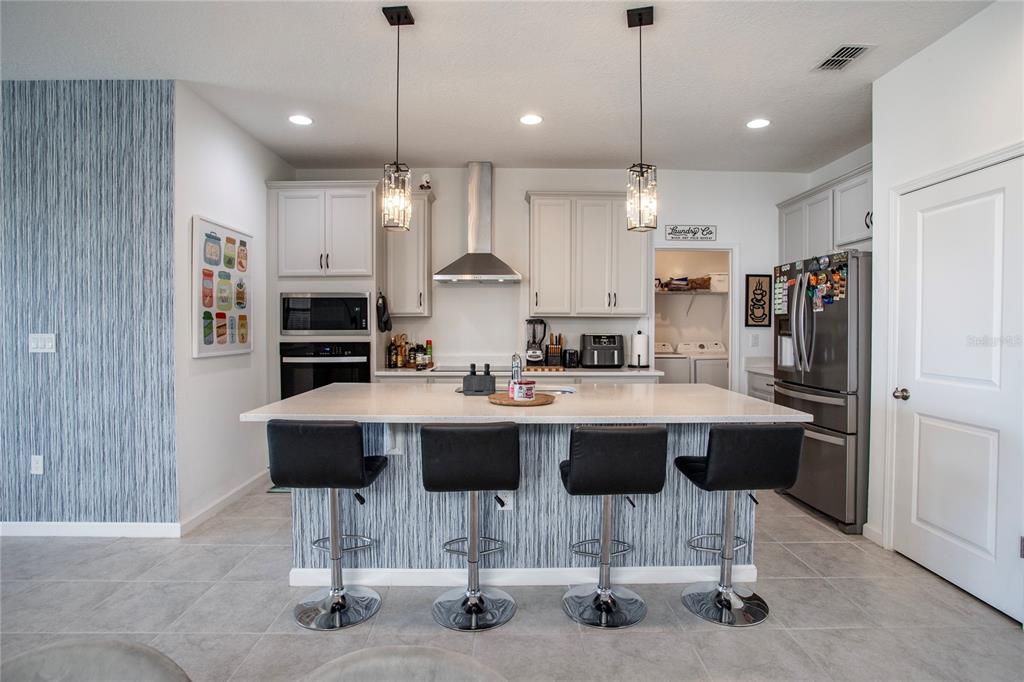 4724 Cragmere Loop Clermont, FL 34711 - Photo 6 of 37 a kitchen island with stainless steel appliances kitchen island granite countertop a table chairs in it and wooden floors