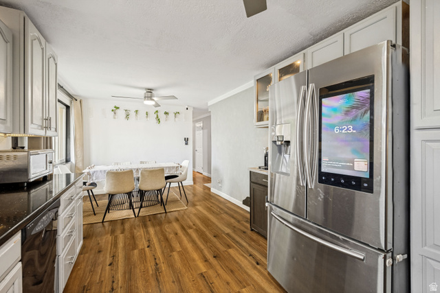 1215 8th Street Ogden, UT 84404 - Photo 11 of 39 Kitchen area featuring stainless steel appliances, wood-finish flooring, white cabinetry, dark countertops, and a dining space