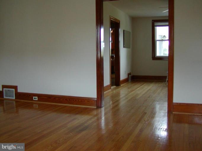 920 Calwell Road Baltimore, MD 21229 - Photo 3 of 5 an empty room with wooden floor and windows