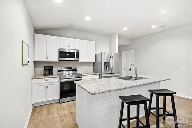 a kitchen with kitchen island granite countertop a stove top oven a sink dishwasher a dining table and chairs