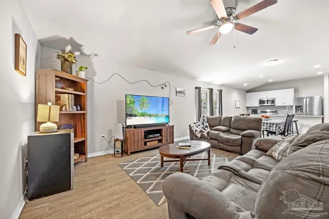 a living room with furniture kitchen view and a window