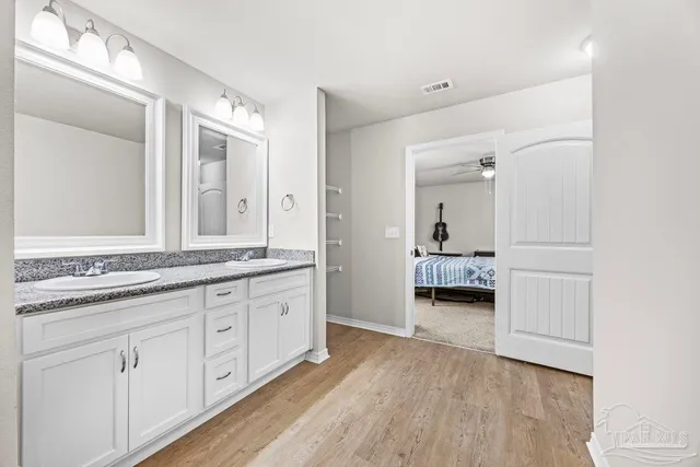 a en suite bathroom with a granite countertop double vanity sink and a mirror