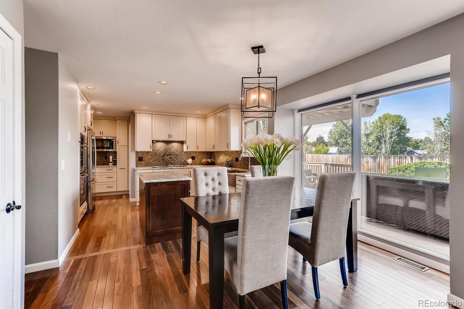 8267 Sweet Water Road Lone Tree, CO 80124 - Photo 5 of 24 a dining room with furniture a chandelier and wooden floor