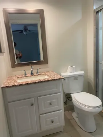 a bathroom with a granite countertop toilet sink and mirror