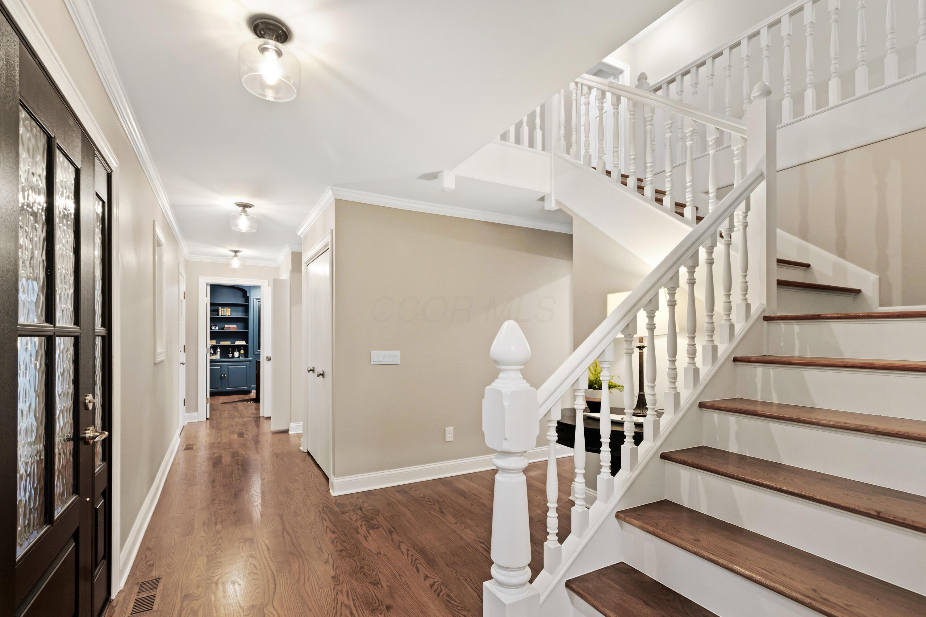 1560 Carriage Road Powell, OH 43065 - Photo 32 of 73 Hardwood flooring throughout the entry, a white staircase with wood-finish treads