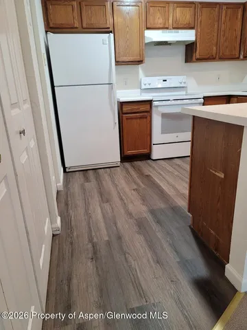 a kitchen with a refrigerator and wooden floor