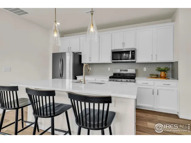 a kitchen with a dining table chairs and refrigerator