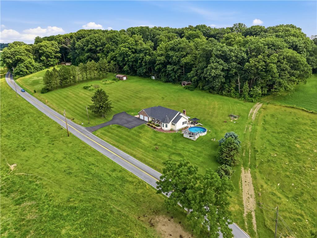9868 Stagecoach Road Kempton, PA 19529 - Photo 2 of 17 An aerial perspective reveals a secluded residence nestled amidst vibrant green fields and mature woodlands.