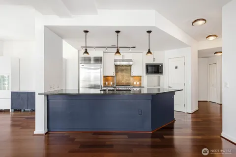 a kitchen with stainless steel appliances granite countertop a sink a stove and a wooden floors