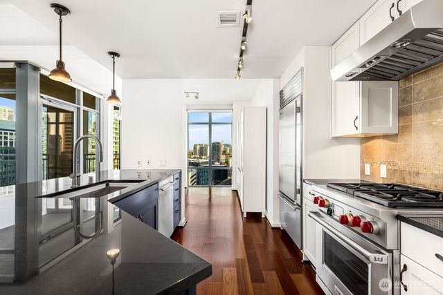 a kitchen with stainless steel appliances granite countertop a stove a refrigerator and a dining table with wooden floor