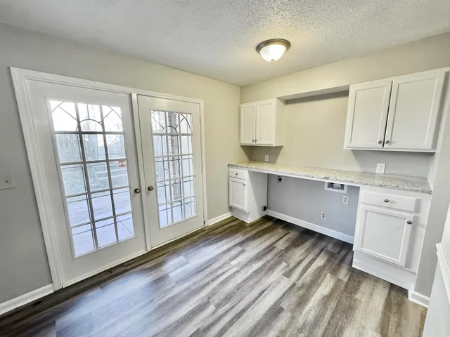 a living room with stainless steel appliances wooden floors and white walls