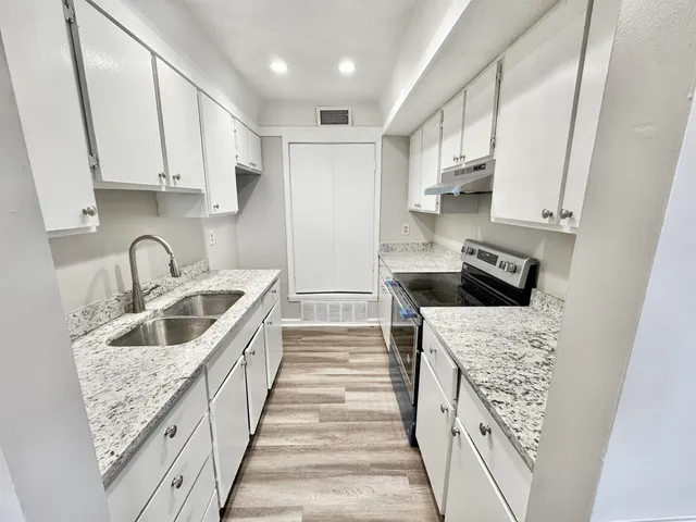 a kitchen with granite countertop a sink and a refrigerator