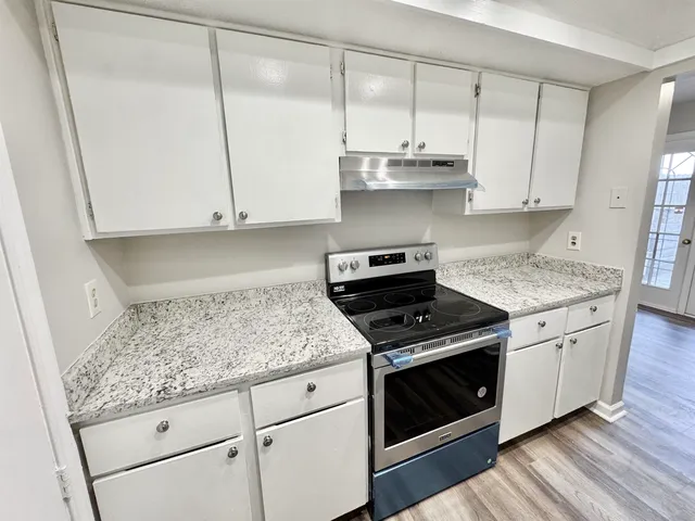 a kitchen with granite countertop white cabinets and a stove