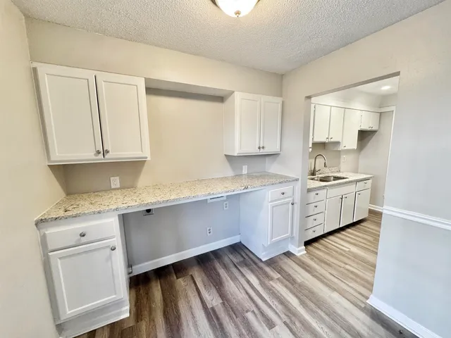 a kitchen with granite countertop white cabinets and white appliances