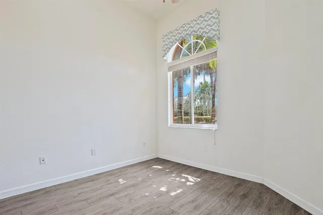 an empty room with wooden floor cabinet and window