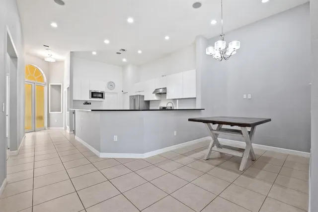 a kitchen with stainless steel appliances granite countertop a sink a stove a refrigerator and white cabinets with wooden floor