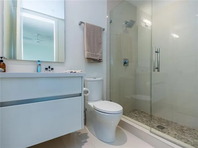 a bathroom with a sink a toilet a mirror and shower