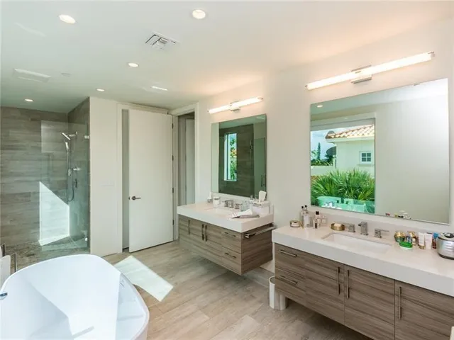 a bathroom with a double vanity sink a large mirror and a bathtub
