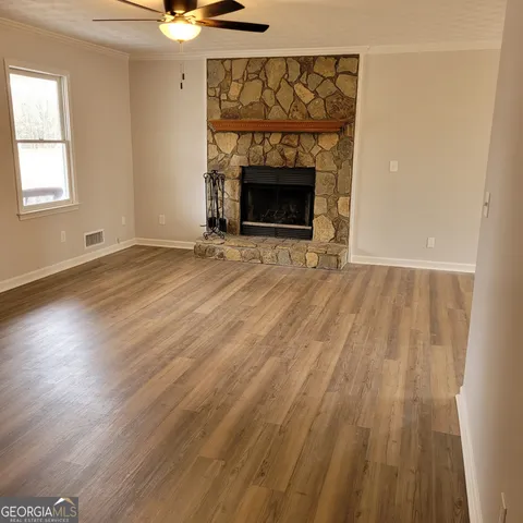 an empty room with wooden floor a fireplace and a window
