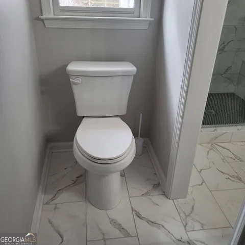 a white toilet sitting next to a small window